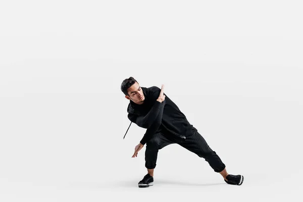 Beau jeune homme portant un sweat noir et un pantalon noir danse breakdance — Photo