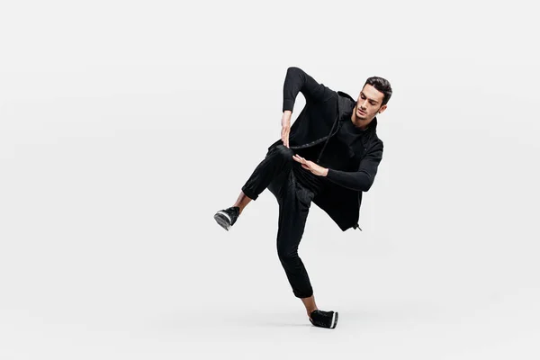 Stilig ung man klädd i en svart tröja och svarta byxor dansar breakdance — Stockfoto