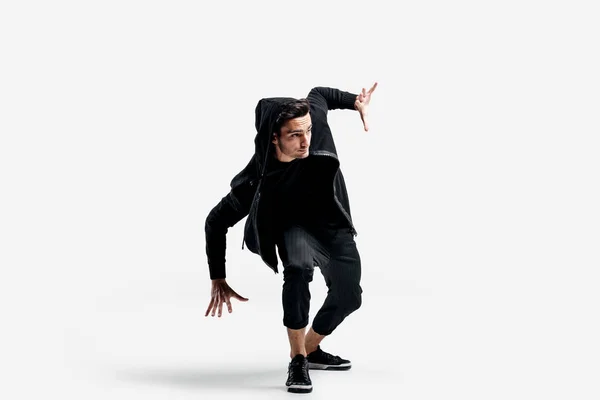 Mörkhårig snygg dansare klädd i en svart kläder gör stiliserade rörelser av gatudans — Stockfoto