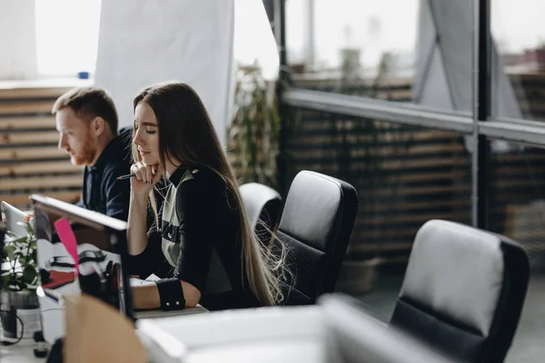 Gadis berambut cokelat muda mengenakan pakaian gaya kantor duduk di meja dan menyimpan buku catatan di tangannya kantor modern ringan — Stok Foto