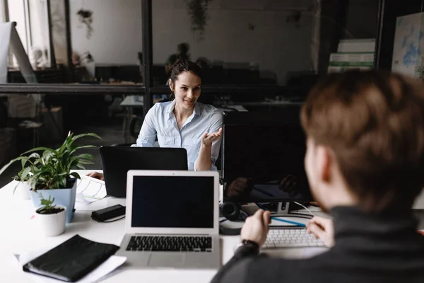 Ung kvinne og mann kledd i kontorklær jobber på pulter i det moderne kontoret utstyrt med moderne kontorutstyr. – stockfoto