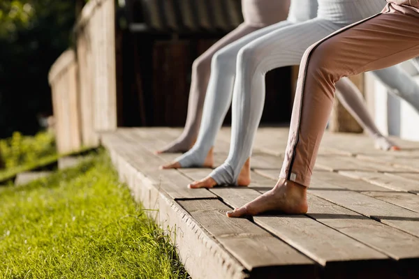 Quatre filles pratiquent le yoga sur un podium en bois dans le jardin en plein air — Photo