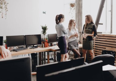 Ofis tarzı giysiler giymiş üç güzel genç kadın birlikte durmak ve modern ofiste görüşmeler