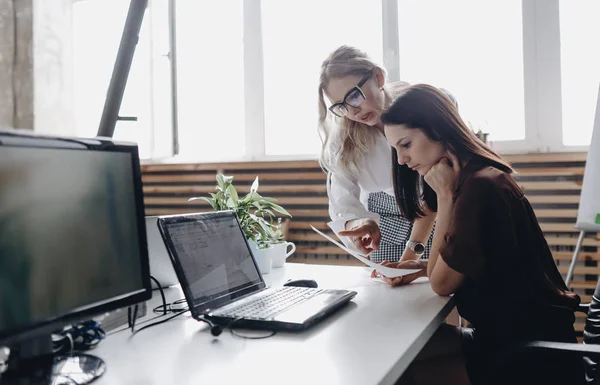 To unge, vakre kvinner i kontorklær jobber sammen med en bærbar pc i et moderne kontor. – stockfoto