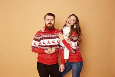 Komik kız ve bir adam kırmızı giymiş ve beyaz kazak geyik ile birlikte stüdyoda bej renkli bir arka plan üzerinde bekletin.