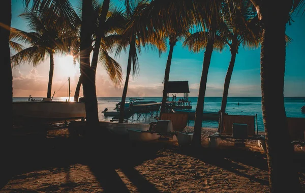 Trou aux Bich 'te güzel bir günbatımı, Mauritius. İskelenin manzarası ve palmiye ağaçları arasında kayıklar.