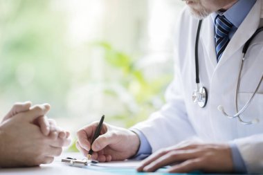 Doktor ve hasta tıbbi cerrahi notlar alıyorlar.