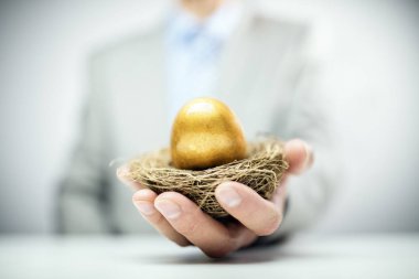Retirement savings golden nest egg in a businessmans hand clipart