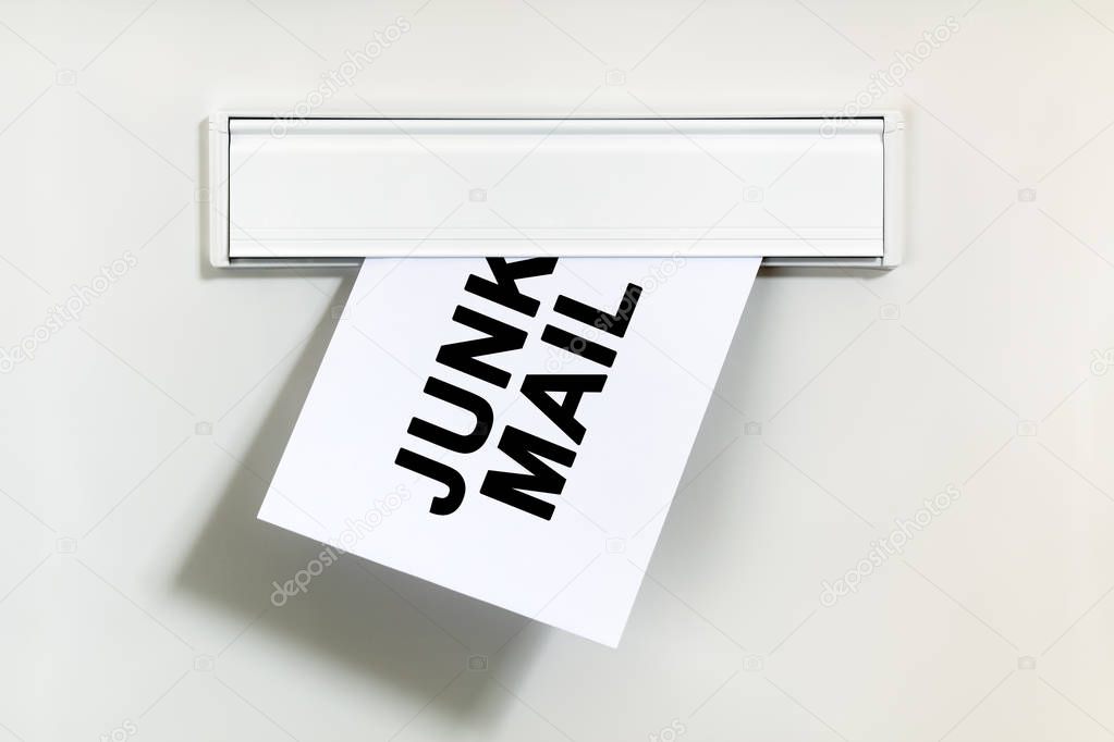 Junk mail or spam on letter being delivered through a letterbox concept for unsolicited mail or e-mail