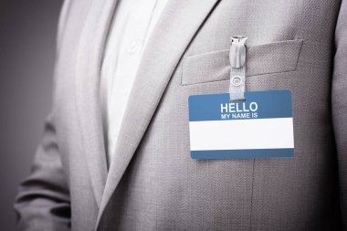 Businessman at an exhibition or conference wearing a Hello my name is security identity name card or tag clipart
