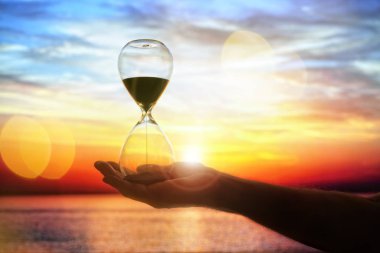 Hourglass time at sunset background with copy space clipart