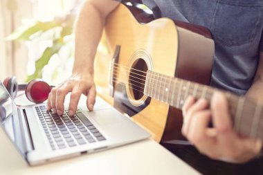 Müzisyen akustik gitar çalmak ve bilgisayarda müzik kayıt veya fom online ders öğrenme
