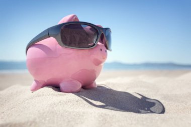 Yaz aylarında sahil plajda güneş gözlüğü ile Piggy banka