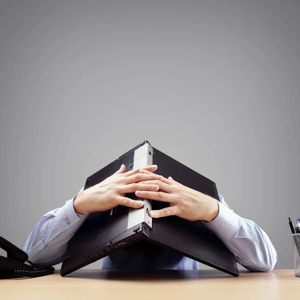 欲求不満と過労のビジネスマンは 助けを求めてラップトップコンピュータの下に彼の頭を埋める — ストック写真