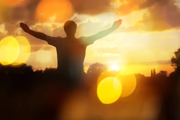 Silhouet Van Een Man Met Handen Opgeheven Het Zonsondergang Concept Stockafbeelding