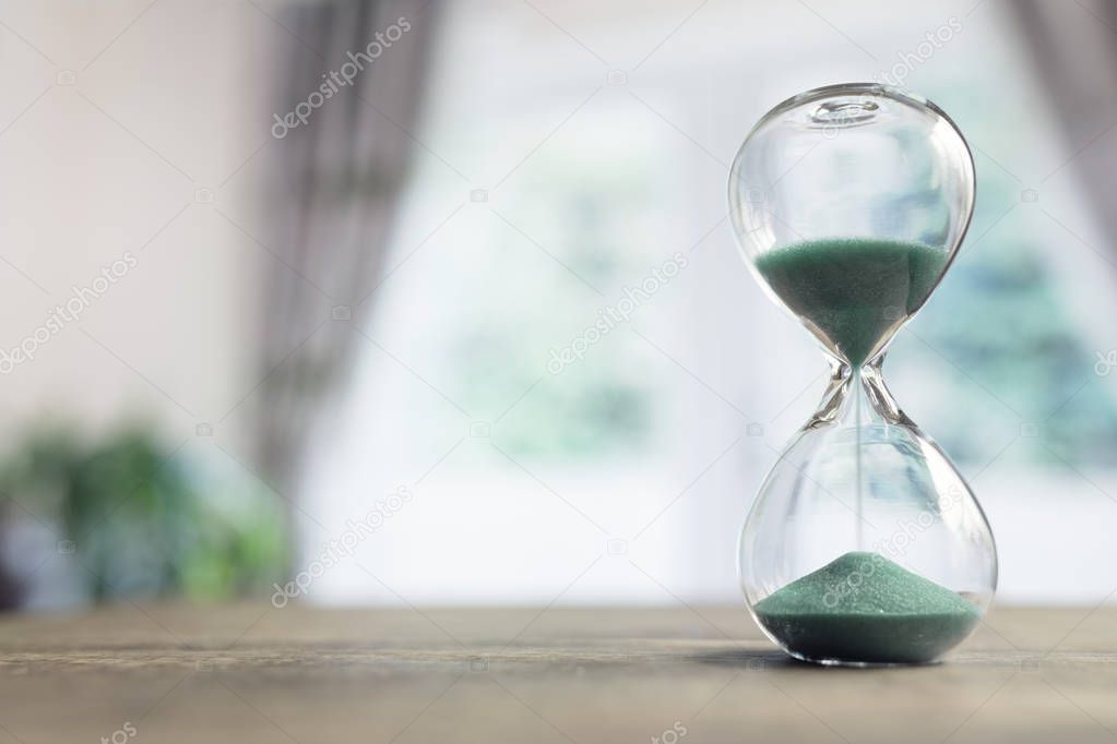 Hourglass time passing on table in room by window