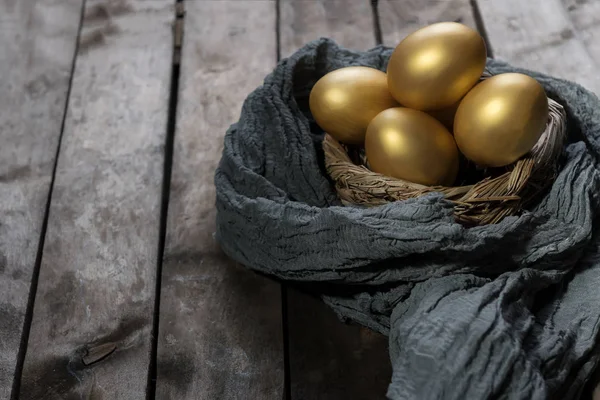 Golden eggs in nest on dark vintage wooden background