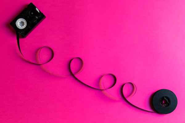 Retro film for old video camera on al pink paper backgound, abstract creative concept. Retro 80s. Minimalism