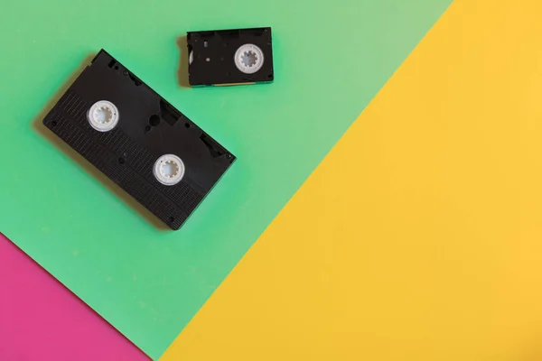 Due videocassette retrò susfondo di carta a tre colori. Immagine flat lay, concetto minimale — Foto Stock