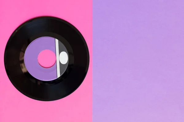 Un disco in vinile obsoleto su uno sfondo di carta di due tonnellate: rosa e viola, cultura pop. Vista dall'alto. Minimalismo, vista dall'alto con spazio di copia — Foto Stock