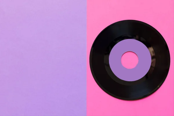 En föråldrad vinylskiva på en två tons pappers bakgrund: rosa och violett, pop kultur. Topp-vy. Minimalism, toppvy med kopierings utrymme — Stockfoto