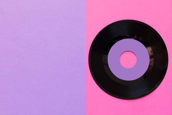One outdated vinyl disc on a two-ton paper background: pink and violet, pop culture. Top view. Minimalism, top view with copy space