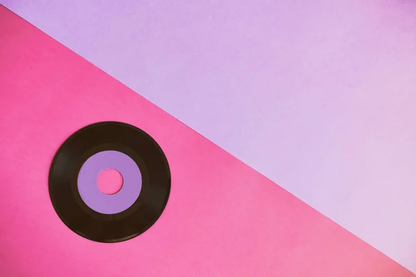 Un disco in vinile obsoleto su uno sfondo di carta di due tonnellate: rosa e viola, cultura pop. Vista dall'alto. Minimalismo, vista dall'alto con spazio di copia — Foto Stock