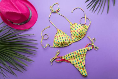 Mor veya mor arka planda palmiye yaprakları ve bikini ile yaz arka plan, seyahat ve tatiller kavramı, üst görünüm