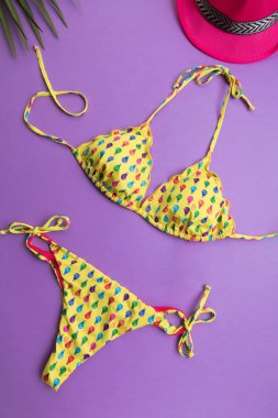 Palmiye yaprakları ile yaz arka plan, pembe moda şapka ve menekşe veya mor arka plan üzerinde bikini, seyahat ve tatiller kavramı, üst görünüm