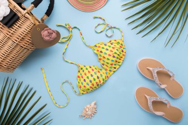 Palmiye yaprakları ile yaz arka plan, moda şapka, Bikini, Flip flop, Açık pastel mavi arka plan üzerinde saman plaj çantası, seyahat ve tatiller kavramı, üst görünüm