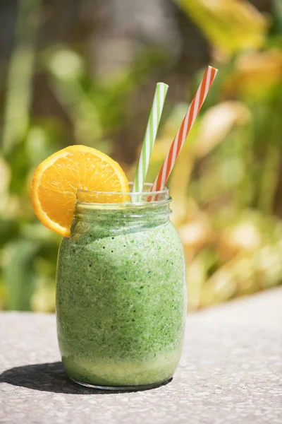 Yaz sağlıklı detoks içecek: parlak öğle güneşinde bir şehir parkı veya bahçesinde harmanlanmış yeşil yüzlü