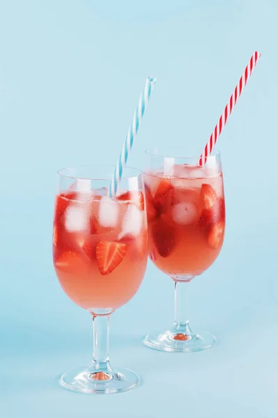 Cocktail de verão de morango fresco e cubos de gelo. Dois copos com morango, gelo e vinho - sangria de morango em um backgound azul de pastel, minimalismo — Fotografia de Stock