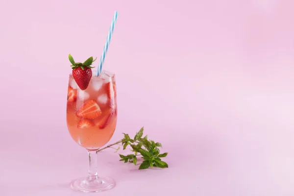 Cocktail estivo di fragole fresche e cubetti di ghiaccio. Bicchiere con fragola, ghiaccio e vino - sangria di fragole su sfondo rosa pastello, minimalismo — Foto Stock