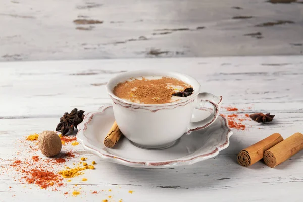 Beautiful cup of traditional indian masala chai tea on with star anise and cinnamon on a shabby wooden texture background, with space