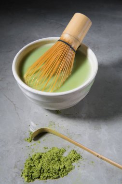 gri mermer üzerinde bir kase içinde bambu chasen ve bambu kaşık ile yeşil çay matcha latte. Japon çay seremonisi konsepti