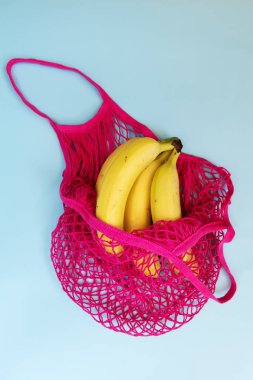 Pastel mavi arka plan üzerinde fuşya eko pamuk dize çanta üç sarı olgun muz