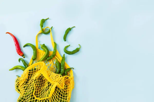 Креативне компонування зеленого перцю чилі. Зелені овочі в жовтій сумці на пастельному синьому фоні. Купа зеленого гострого перцю під назвою фрітельлі — стокове фото