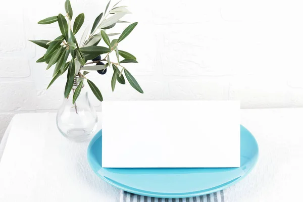 Минималистичная композиция с карточками макет для приглашения, меню, место карты на пастельно-голубой фарфоровой пластины с оливковой веткой на белом фоне — стоковое фото