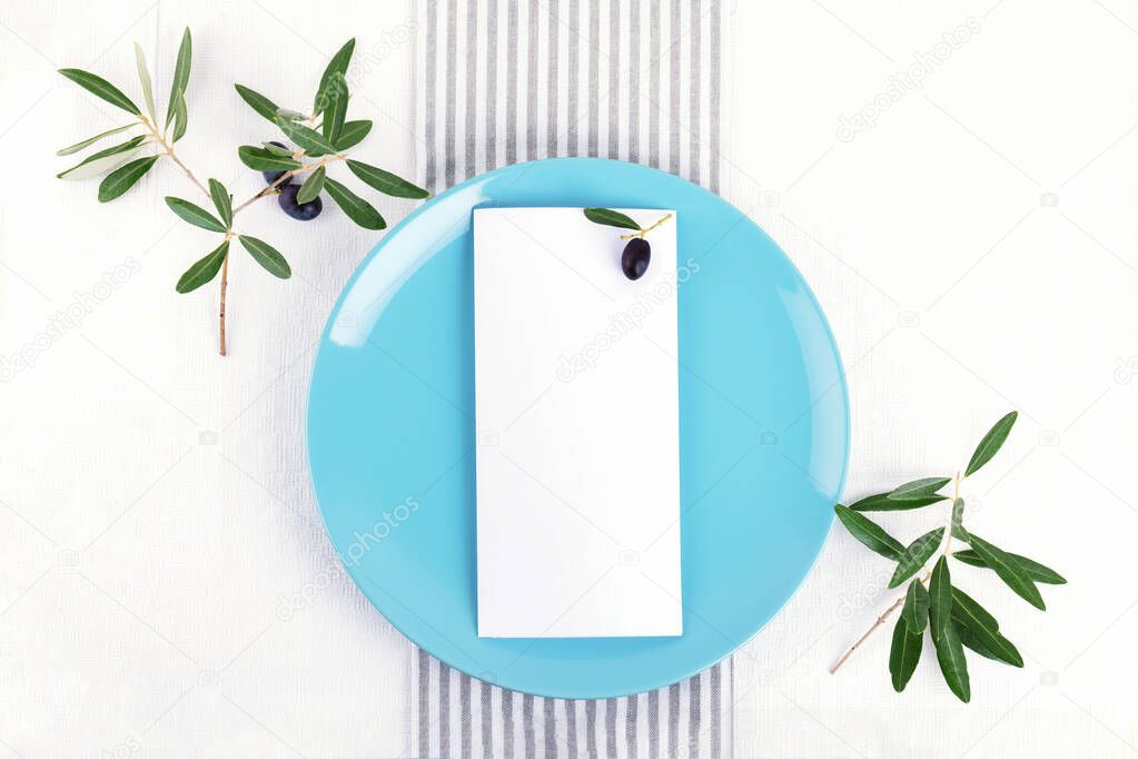Festive wedding, birthday table setting with golden cutlery, olive branch, pastel blue porcelain plate. Blank card mockup. Restaurant menu concept