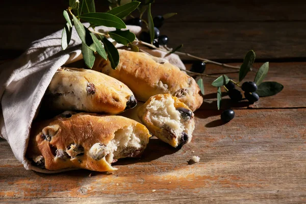 Traditional italian puccia breads with black olives in a cotton bag, made in Salento, Puglia on a wooden background