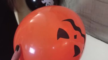 Turuncu bir balona yaklaş, yüzünde Jack 'O Lantern' ın yüzü olan, hazırlan ve Cadılar Bayramını evde kutlamak için evi süsle.