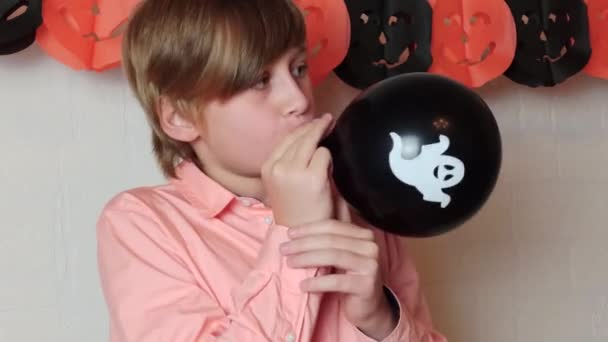 Blond Pojke Ler Uppblåsa Den Svarta Ballongen Med Ett Spöke — Stockvideo