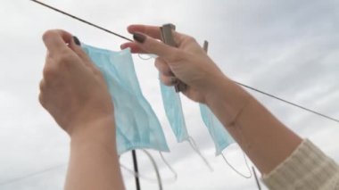 Bir kadın, Covid-19 'da yeniden kullanılmak üzere tek kullanımlık tıbbi bir maskeyi kurutmak için takılıyor. Coronavirus ekonomiyi ve sağlığı mahvediyor.