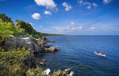 Ship with tourists admiring sheer cliffs of the northern coast of Bornholm island - Helligdomsklipperne (Sanctuary Rocks), Denmark clipart