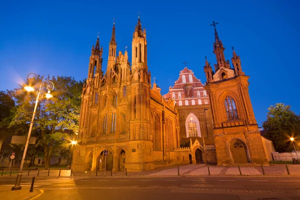 立陶宛维尔纽斯老城Maironio街灯火通明的哥特式圣安妮教堂的夜景 背景中的圣弗朗西斯和圣伯纳德教堂 — 图库照片