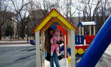 Annem, sokakta küçük bir çocuk, göçebeller, gün boyunca bir ev ile parlak bir oyun alanında oynuyor