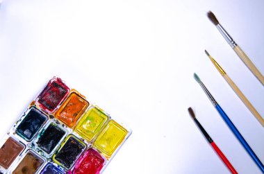 Beyaz arka plan üzerindeki boyalar için suluboya ve fırçalı palet. Suluboya boyalar. Fırçalar. Üst ve ön görünüm