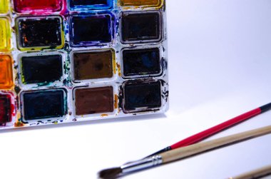 Beyaz arka plan üzerindeki boyalar için suluboya ve fırçalı palet. Suluboya boyalar. Fırçalar. Üst ve ön görünüm