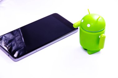 Nisan 2019. Los Angeles, Amerika Birleşik Devletleri. Beyaz bir arka plan ve bir akıllı telefon ile Yeşil plastik Android rakam. Şekil, logo Android, Google