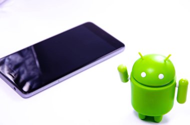 Nisan 2019. Los Angeles, Amerika Birleşik Devletleri. Beyaz bir arka plan ve bir akıllı telefon ile Yeşil plastik Android rakam. Şekil, logo Android, Google